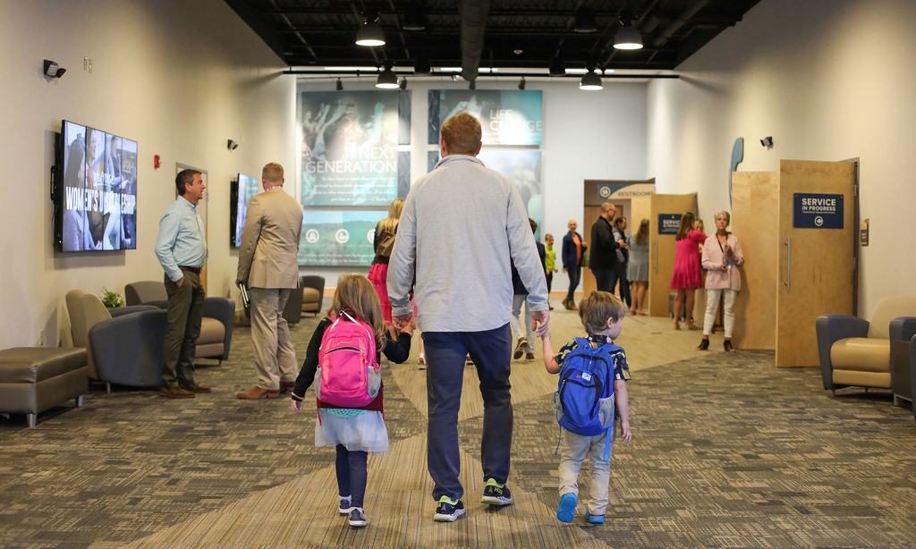 dad holding kids hands walking through Powdersville campus lobby