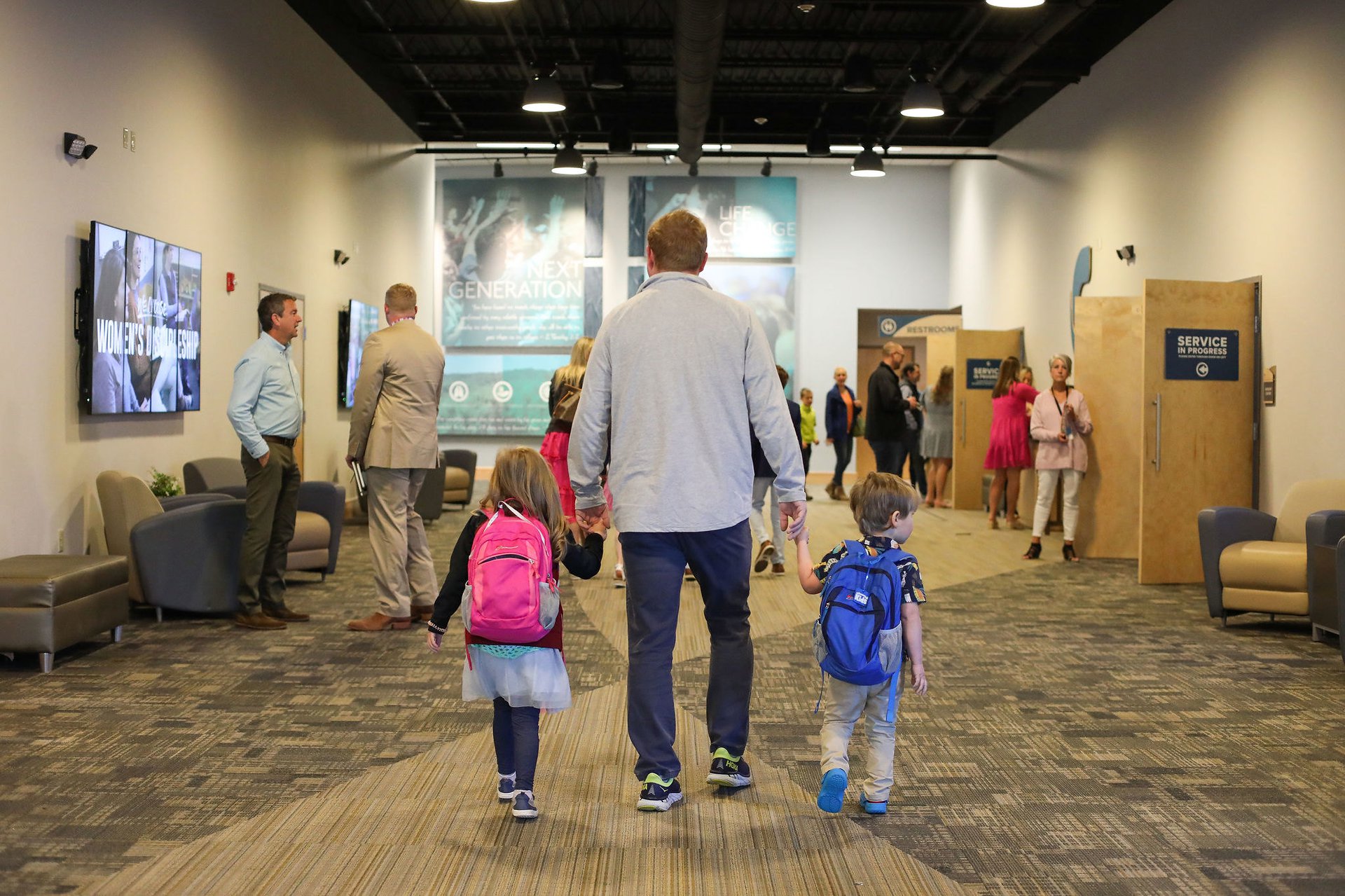 dad holding kids hands walking through Powdersville campus lobby