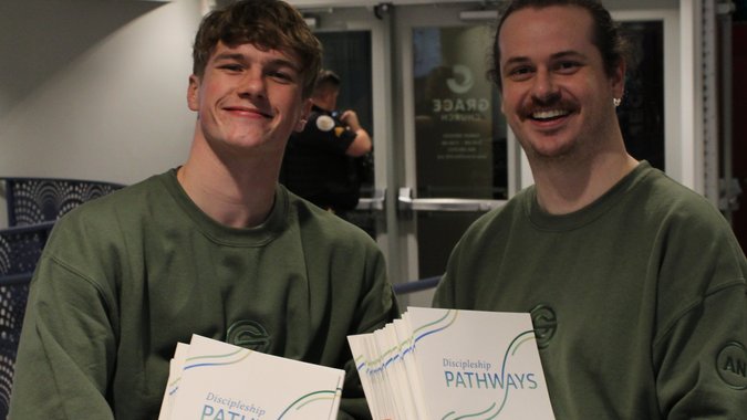 Men holding up Discipleship Pathways booklets