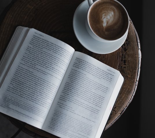 Open Bible on table with latte