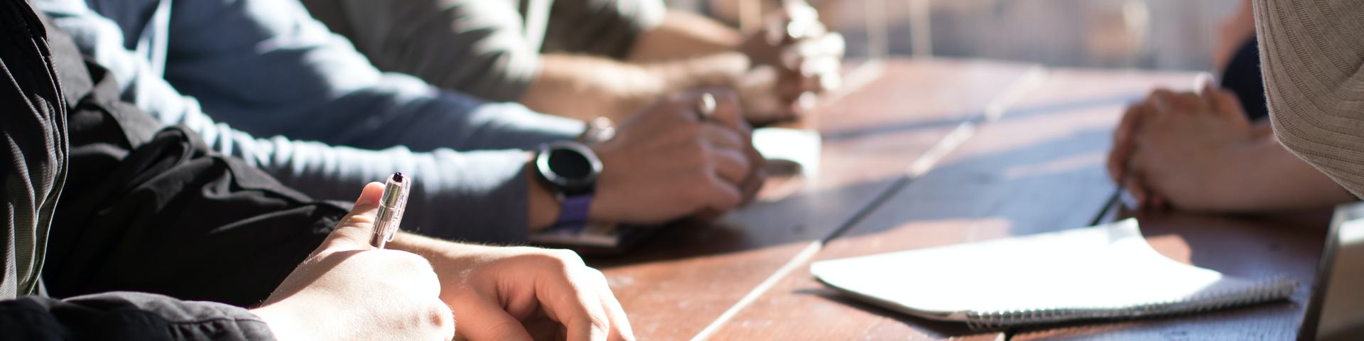 People talking and taking notes at a table