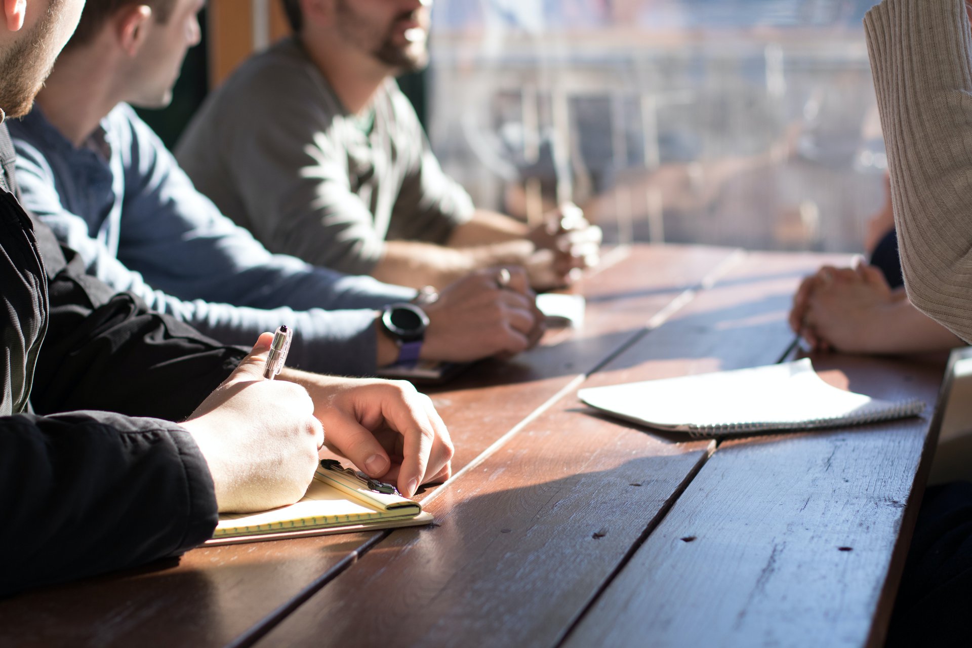 People talking and taking notes at a table
