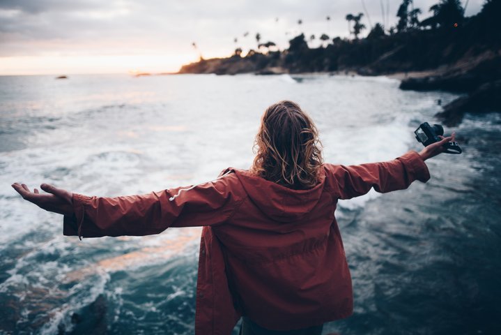 Woman Standing by Water with Open Arms